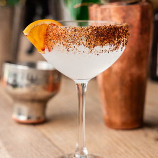 Mezcalita au sel piment et hibiscus et un quartier d'orange sur le bord du verre.