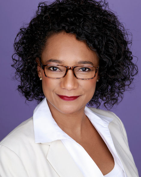 business headshot of a woman in a white suit and purple background