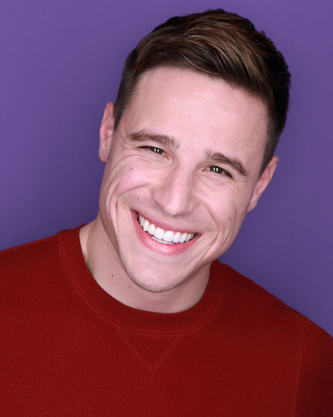 Actor headshot of handsome white man wearing a red shirt, shot in studio with a purple background