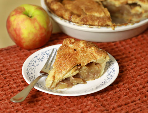 Product shot of fresh apple pie on a white plate shot in studio with a blurred background