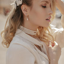 curly-blonde-young-woman-with-pearl-jewelry-dressed-white-blouse-looks-calm-poses-city-cen
