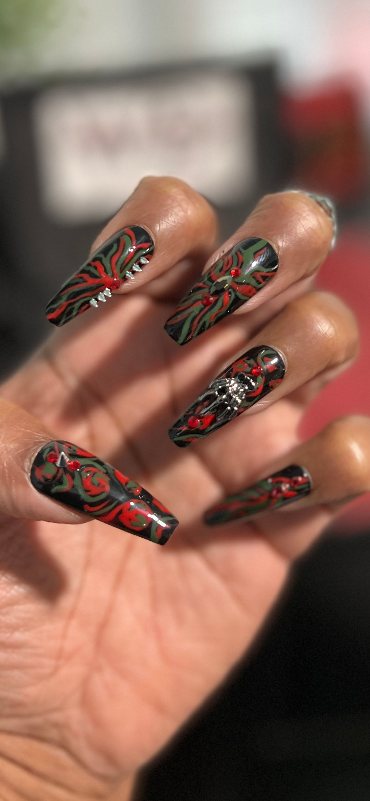 black, red and green press-on nails on a hand