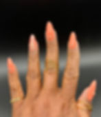 Almond shaped press-on nails, peach colored with rhinestones on a hand