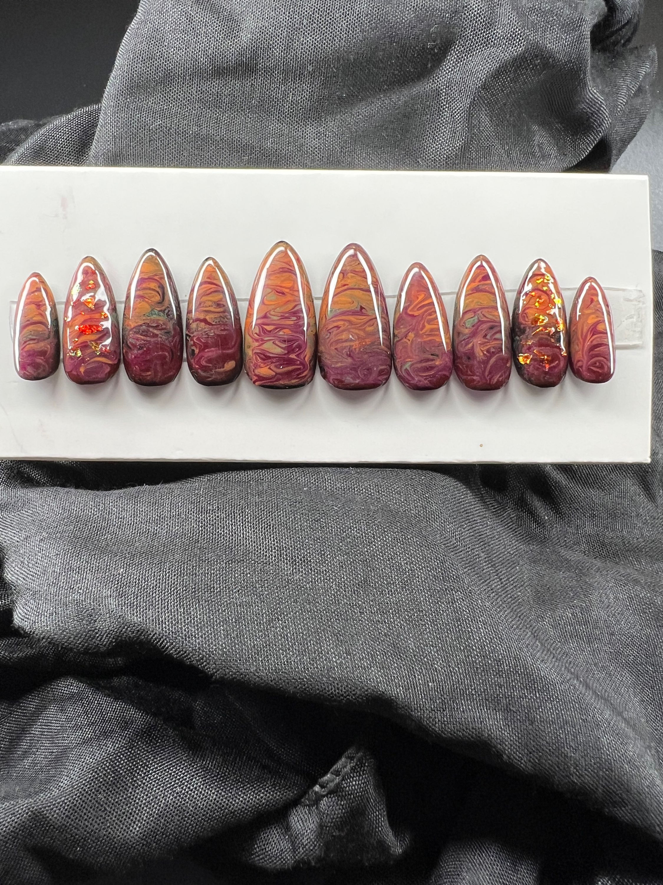 Almond shaped, brown colored, press-on nails on a display card