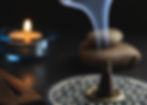 Cone incense burning with a candle in the background.