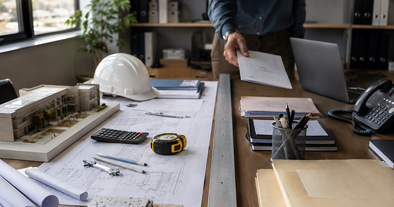 School facilities accounting workspace split by a precise straight line, separating construction project materials from general operational paperwork to symbolize clear capital-versus-operations coding.