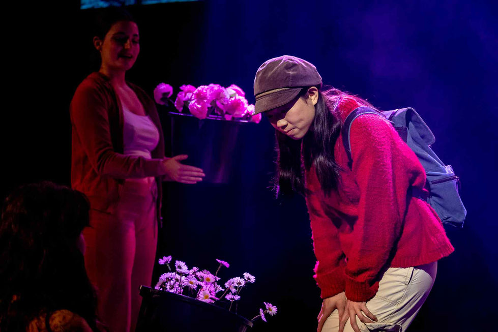A production photo of the lead looking at a bucket of flowers