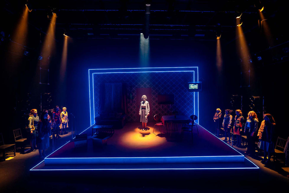A production shot of the full stage with the main character standing in a spotlight.
