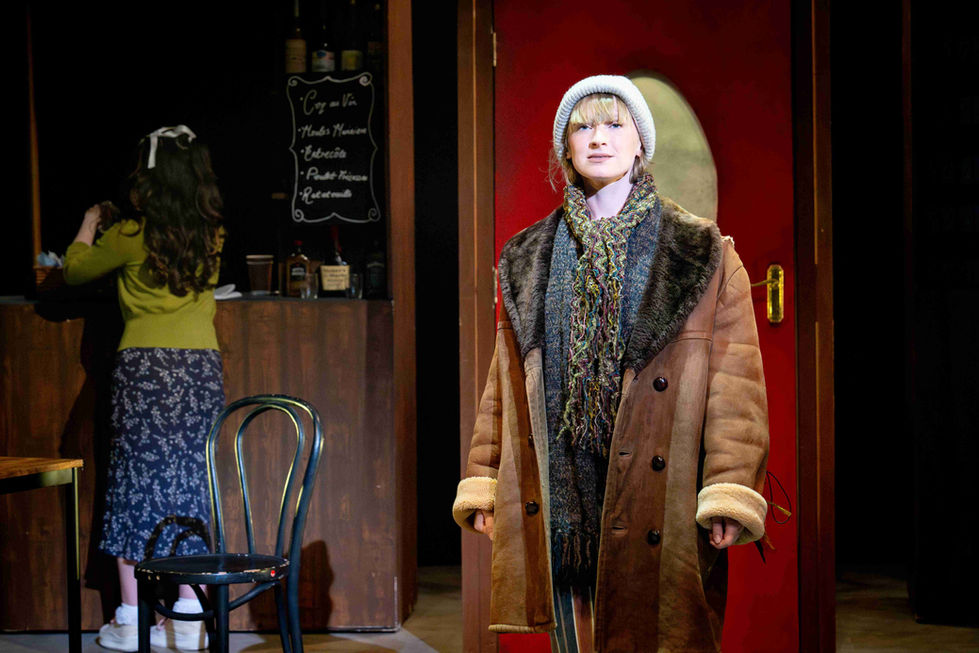 A production photo of a character standing in a café.