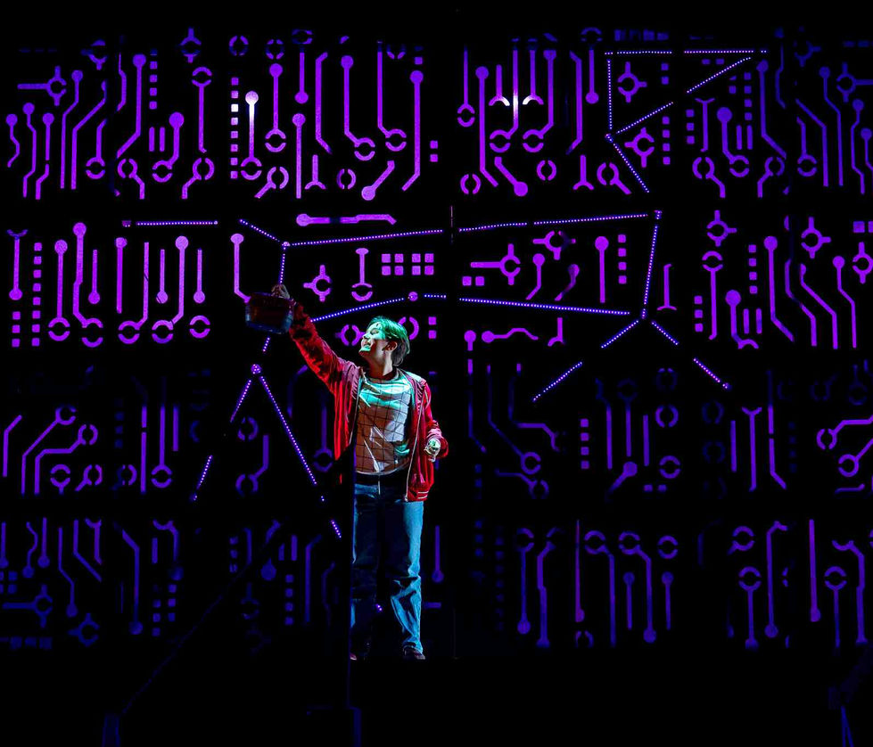 A production photo of the lead character pointing at a lit up dog outline