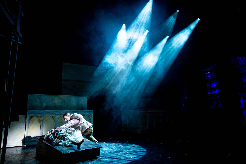 A production photo of a character on their deathbed