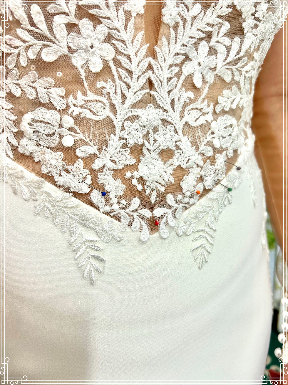 Close-up view of a wedding dress bodice being pinned for alterations