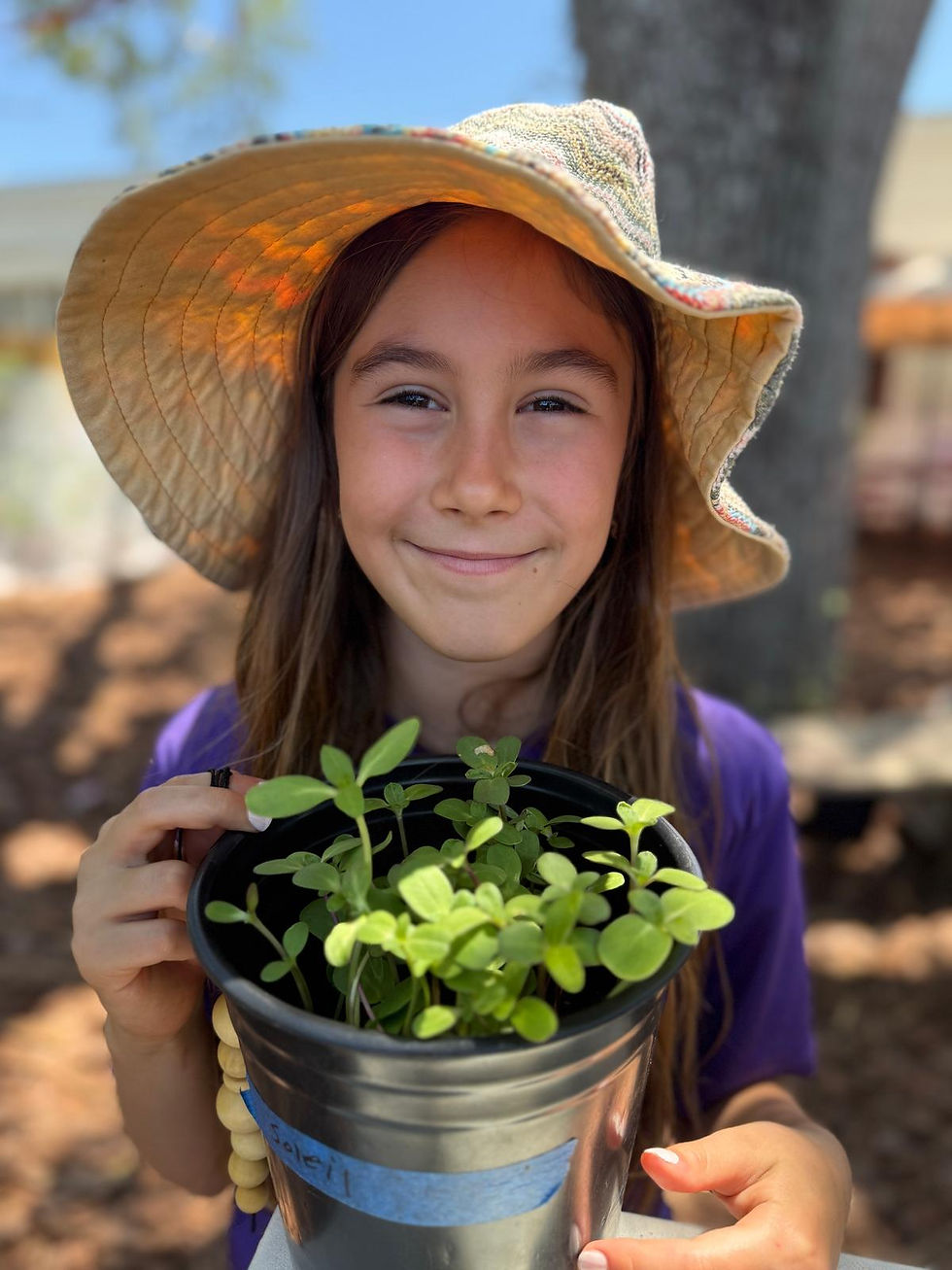 Student smiles with potted herbs