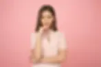 Smiling woman with hand on chin, pink background