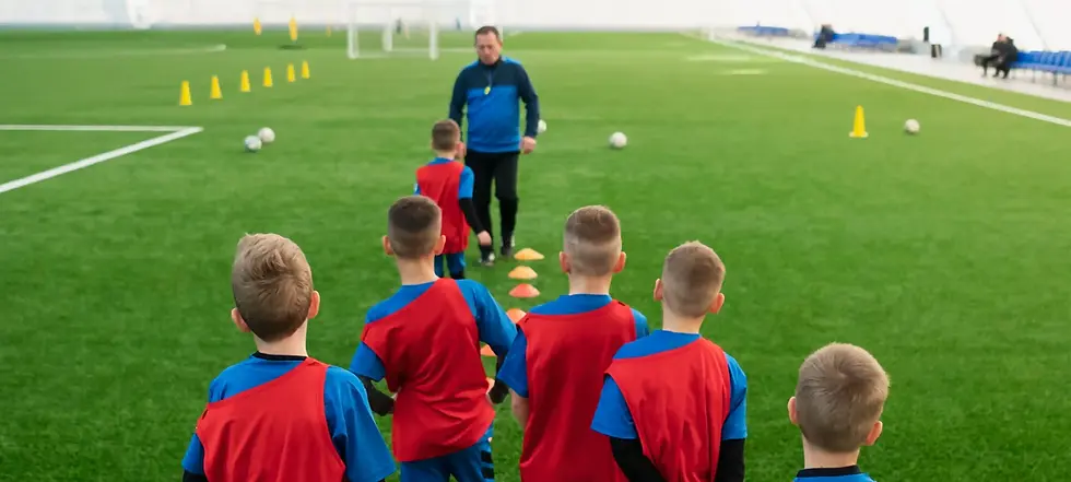 Young soccer players in red and blue uniforms listen to their coach LilChampFC