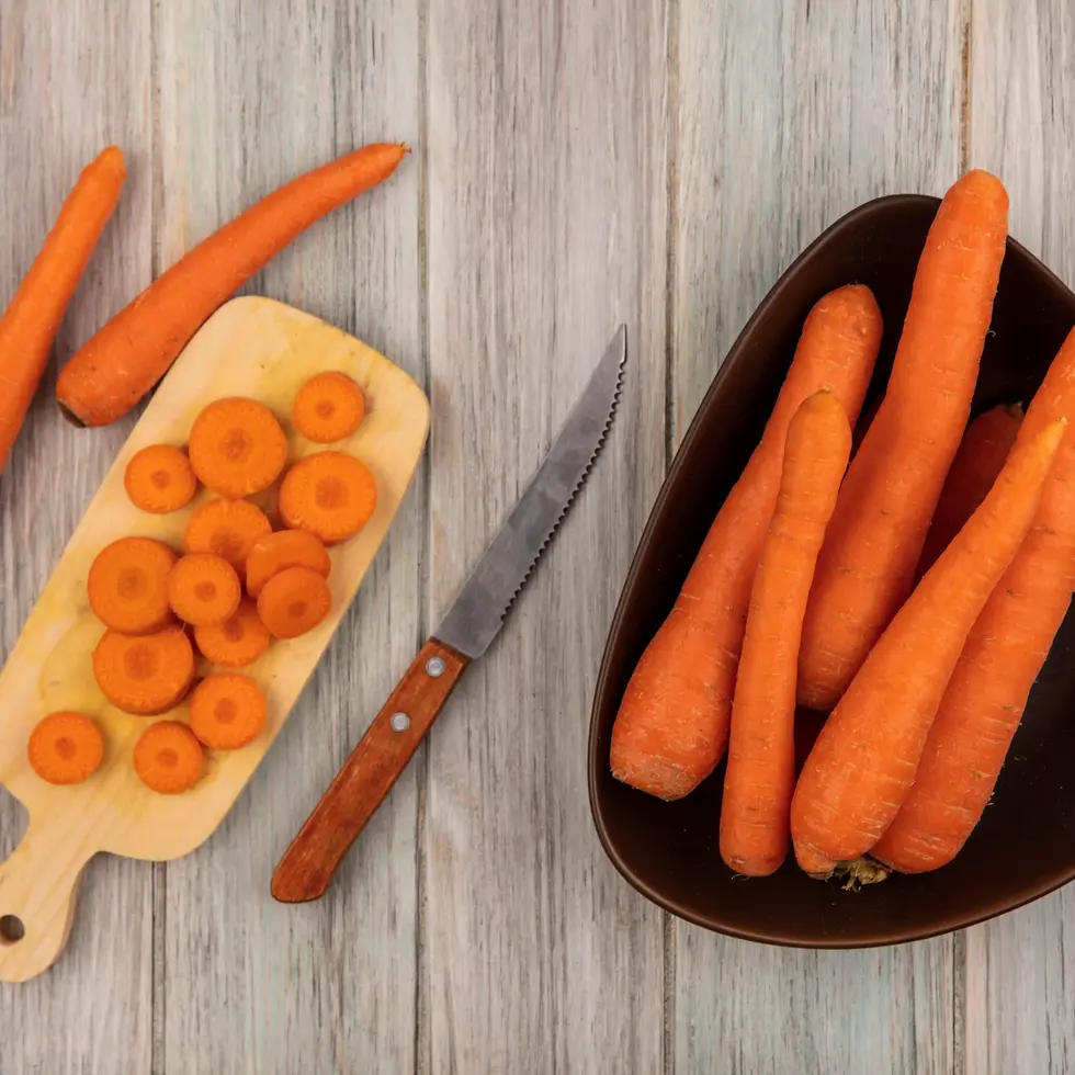 Chopped and whole carrots, knife, wooden cutting board