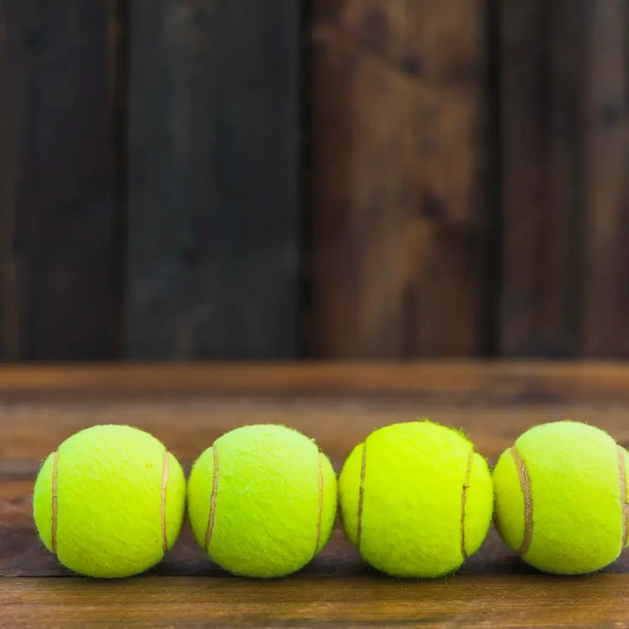 Four tennis balls on wooden surface