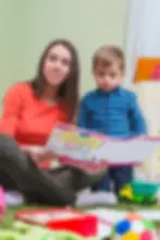 Smiling mother reading book to toddler