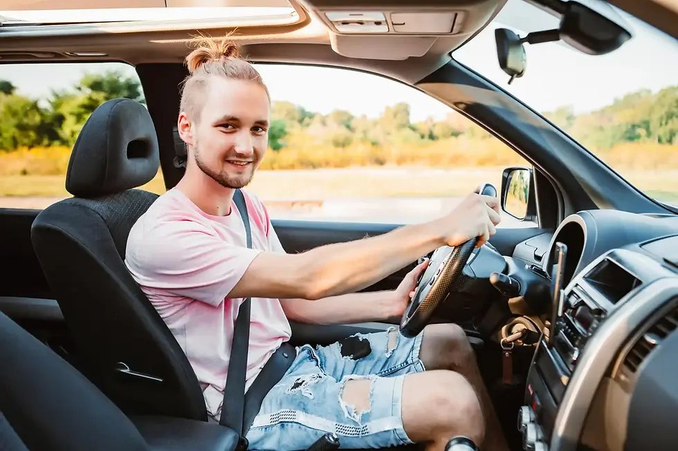 Young man smiling in car's driver seat
