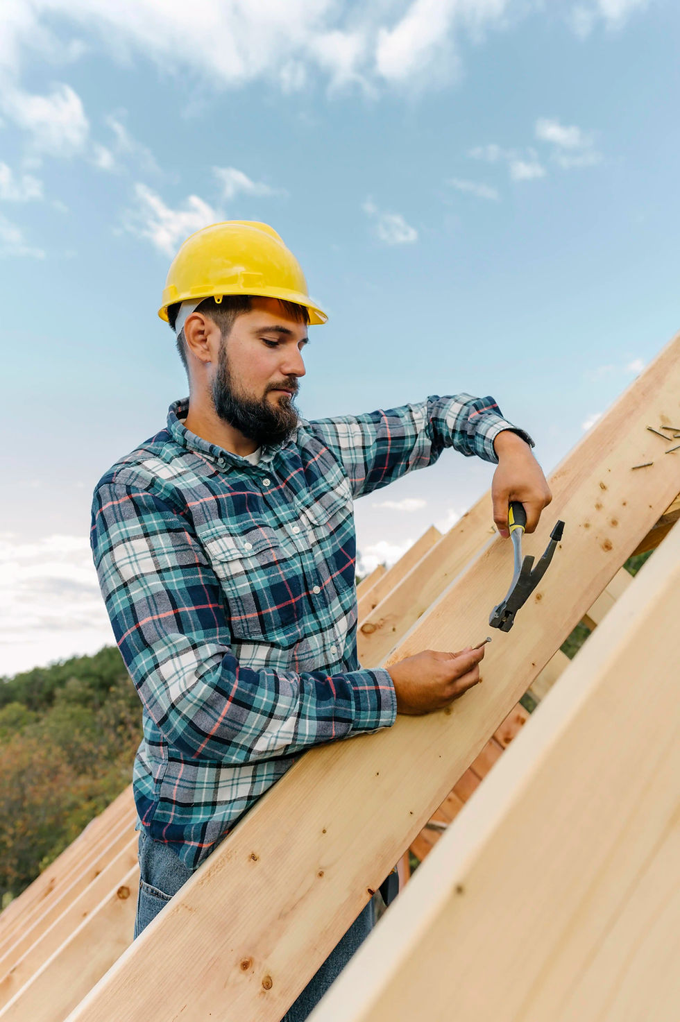 Construction worker hammering wood on a roof