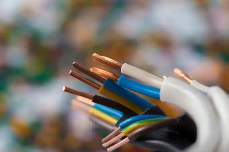 Close-up of multicolored electrical wires with exposed copper conductors, background blur.