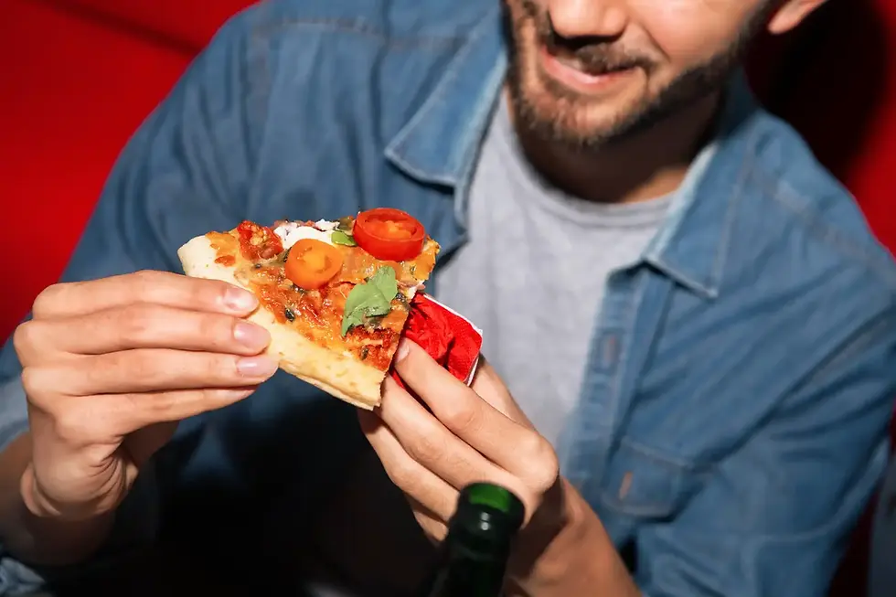 Man holding delicious pizza slice with tomatoes and basil, ready to eat.