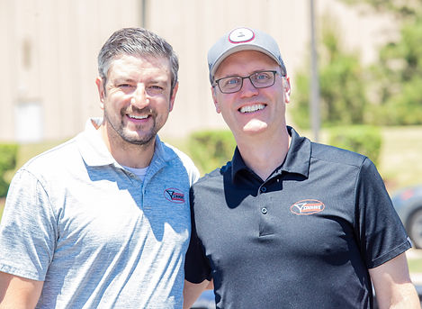 Two Simmons Knife & Saw team members posing together during the company's 80th Anniversary Celebration at its headquarters in Glendale Heights, Illinois