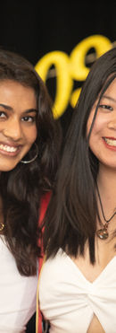 Two women wearing white outfits celebrating their graduation together at Illinois State University, smiling and posing during a graduation celebration event on campus.