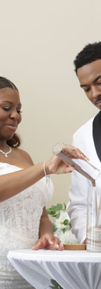 Bride and groom performing unity sand ceremony at Chicago wedding reception at Manzo’s Banquets & Catering, wearing white wedding attire while pouring sand into glass vase symbolizing unity