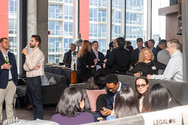 view of legal professionals networking inside Vu Rooftop during the In-House Connect mixer in Chicago, with sponsor signage and city views visible.