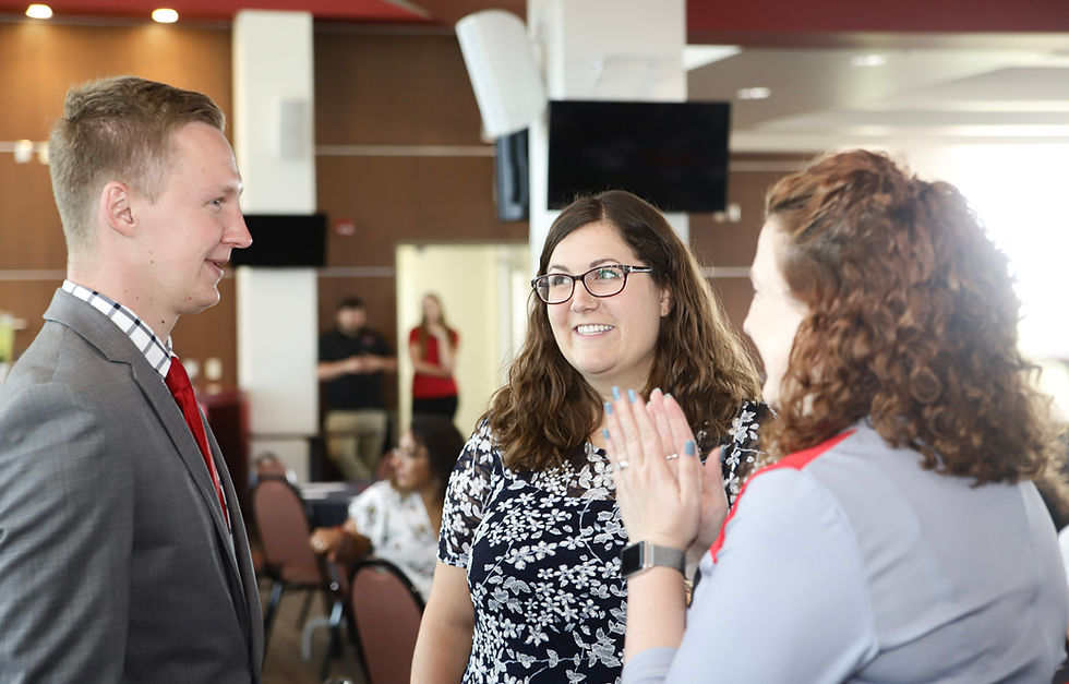 Colleagues engaged in conversation following a keynote presentation at a university event, captured indoors as attendees interact and network after the program.