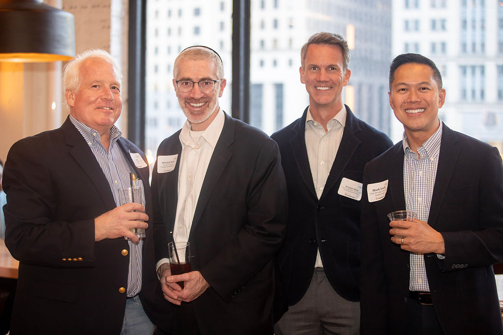 Group of male professionals networking at Chicago corporate event with downtown skyline visible through windows