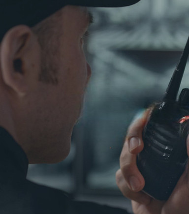 Un agent de sécurité de GPS de dos parle dans un talkie-walkie