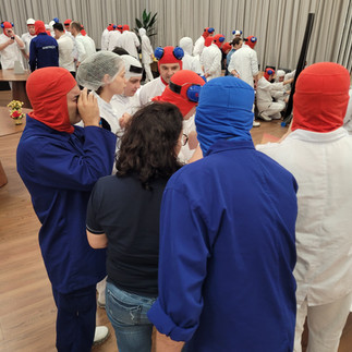 Equipe resolvendo um enigma da Ilha Misteriosa com outros times ao fundo.