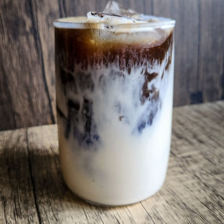 Iced dirty blue matcha latte layered with coconut milk and espresso, showing a natural blue-to-brown gradient in a clear glass.