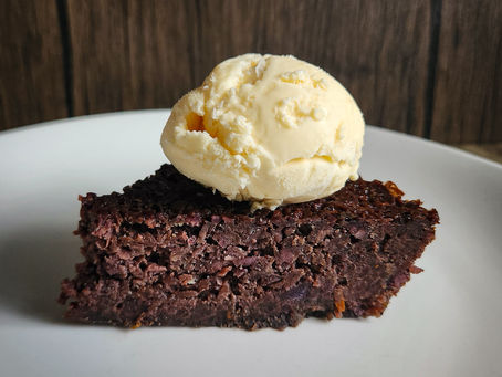 Sweet potato pone baked in a cast iron skillet, dark, glossy, and fully set.