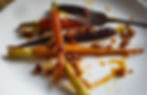 Softly lit photo of plated maple-glazed carrots, fork placed beside for serving.