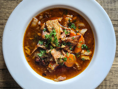 Crispy seared pork jowl sizzling in a heavy pot, golden brown with rendered fat glistening under the heat.