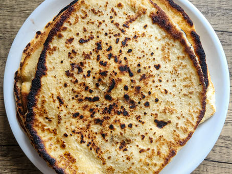 A stack of freshly cooked Greek-style pitas wrapped in a cloth to stay warm.