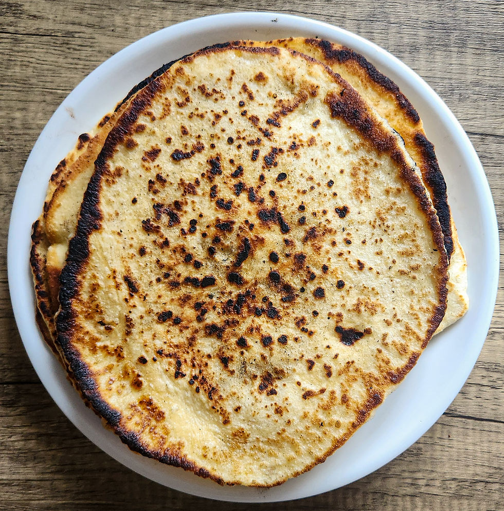 A stack of freshly cooked Greek-style pitas wrapped in a cloth to stay warm.