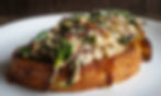 Golden-brown toast piled high with creamy spinach, onions, and cheese, viewed from the side.