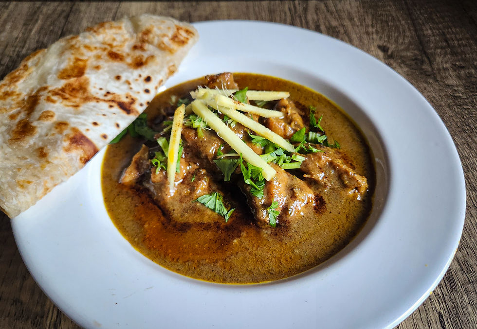 Plate of chicken nihari with paratha, viewed at an angle.