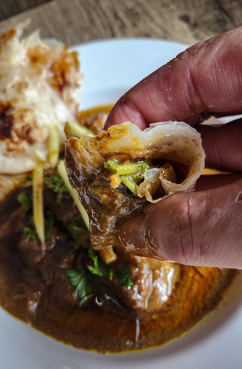 Close-up of paratha stuffed with chicken nihari and garnish.