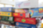 Mixed boxed games and puzzles including Apples to Apples Party Box on a metal shelf