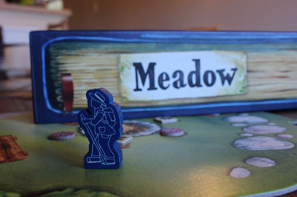 A blue meeple with white outline in a hat and walking stick stands in front of a board game box cover with the word "Meadow"
