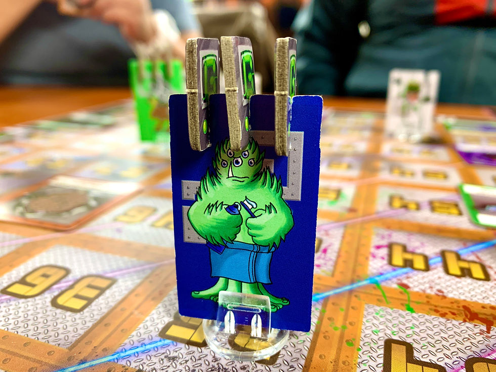 A component token of the character Greygue a green 5 eyed monster on a blue background with three small tokens attached to the top