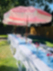 Pink fringe umbrellas with table and chair event rentals.