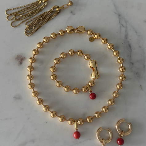 ISOLA Coral necklace and bracelet displayed with raw coral and textured linen, evoking the serenity of Mediterranean islands and the symbolism of circular forms.