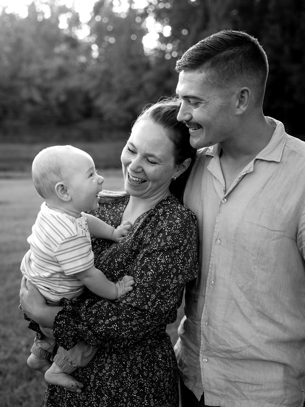 Family session with a happy 6 month old baby boy being held by his mother and his father making him giggle.
