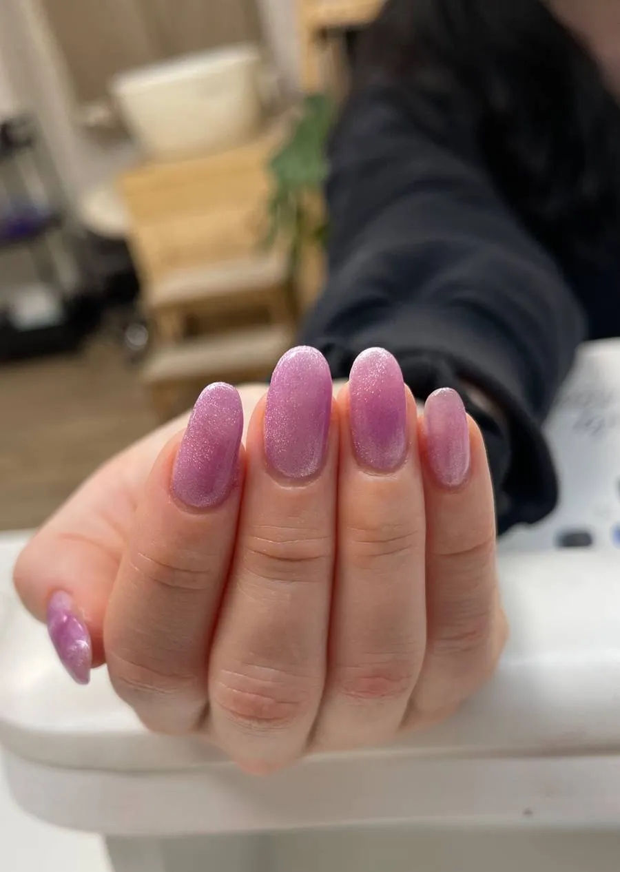Iridescent purple cat-eye nail extensions with a soft shimmer effect.